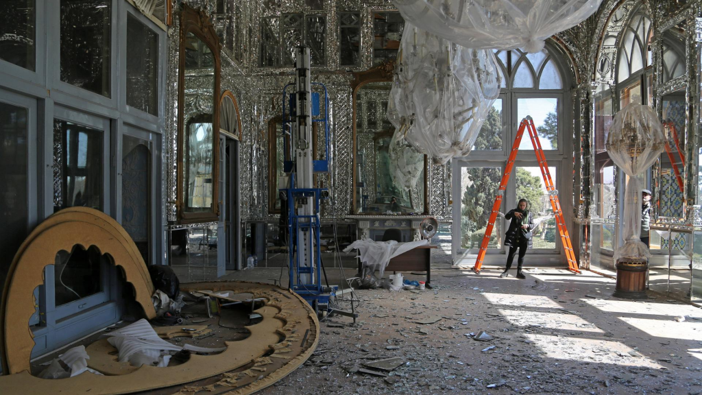 Decorative mirrored room under renovation with plastic sheets, ladders, and debris on the floor; a person stands near an orange ladder by the windows.